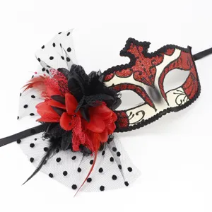 Détail du masque de bal masqué, paillettes rouges et design en filet floral noir.