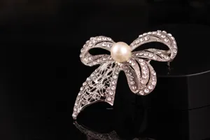 Primo piano di spilla vintage a fiocco con strass e perla centrale per accessori donna.