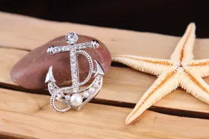 Detailed close-up view of the sparkling rhinestones and pearls on this silver anchor brooch.