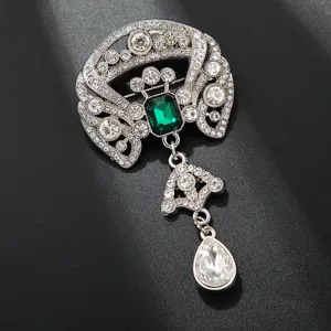 Nahaufnahme Detail der Vintage Kristall Strass Brosche mit gruenem Edelstein und Anhaenger.