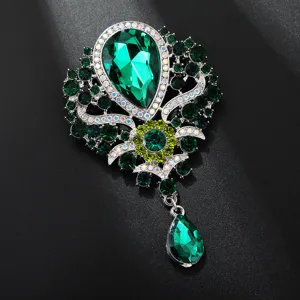 Primo piano dettagliato di una spilla con goccia di cristallo verde vintage con strass scintillanti.
