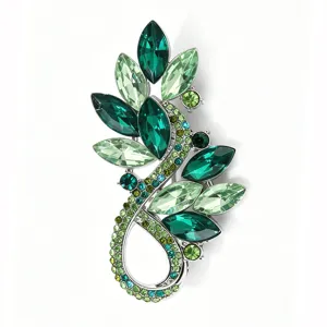 Close-up detail of the luxury green rhinestone leaf brooch, sparkling crystal embellishment.