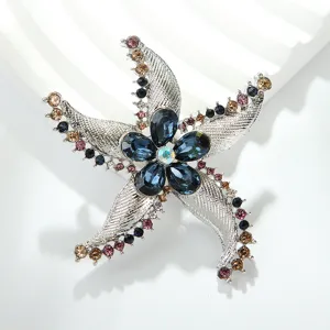 Elegant silver-tone starfish brooch featuring multi-color crystals and dark blue stones.