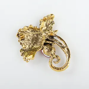 Achterdetail van de gouden bloem blad broche met een veilige speldsluiting en rood accentstukje.