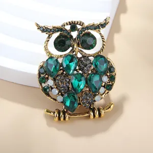 Gros plan détaillé montrant les strass vert émeraude et le design vintage de la broche.