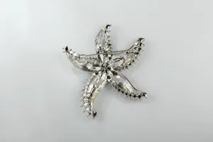 Detailed view of the back of a silver starfish brooch, showing sturdy pin clasp and texture.