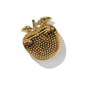 Gold apple brooch detail back view showing secure pin clasp and textured metal finish.