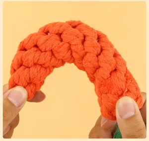 Close-up of a braided orange cotton rope pet teething toy, showing flexible curved shape.