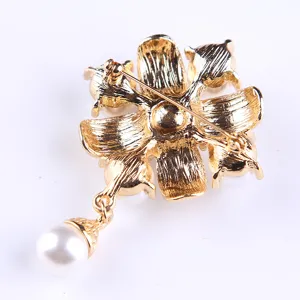 Detailansicht einer goldenen Perlenbrosche, florales Design mit sicherer Nadel auf der Rückseite.