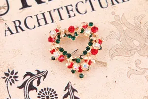Detailaufnahme einer Weihnachts-Herzbroche mit roten und grünen Strasssteinen, Legierung.