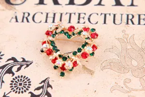 Nahaufnahme der vintage Strass-Herzbroche mit funkelnden roten und grünen Kristallen im Detail.