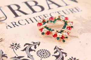 Nahaufnahme einer vintage Strassherz Brosche mit roten und grünen Kristallen verziert.
