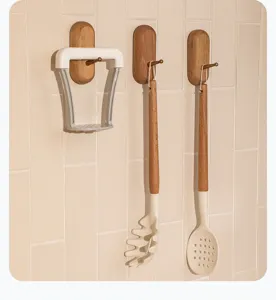 Wooden wall hooks with kitchen utensils like potato masher and pasta spoon for home use.