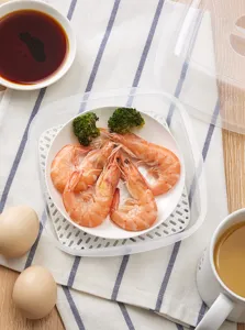 Vista detallada de la caja vaporera transparente para microondas con los alimentos.