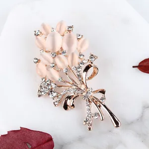 Élégante broche bouquet en or rose ornée de pierres œil de chat roses et de strass.