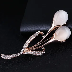 Close-up detail of a rose gold tulip brooch featuring white opal and sparkling rhinestones.