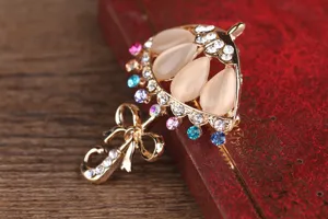 Primo piano dettagliato di una graziosa spilla a ombrello con pietre opale e strass.