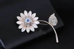 Elegante spilla a girasole con petali in pietra occhio di gatto bianca e strass scintillanti.