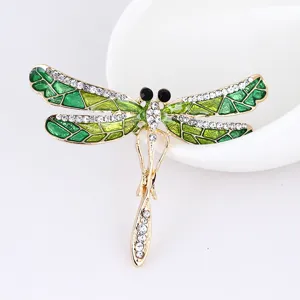 Close-up detail of exquisite dragonfly brooch, featuring green enamel wings and sparkling rhinestones.