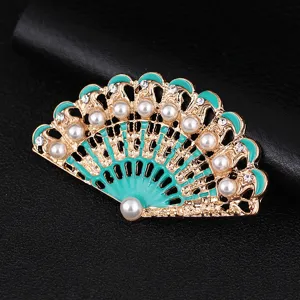 Dettaglio ravvicinato di spilla ventaglio vintage con smalto turchese perle strass.