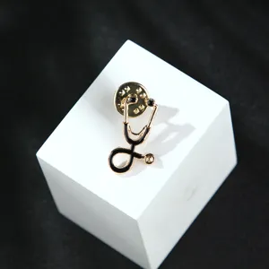Close-up detail of a stylish alloy stethoscope brooch, elegant black and white enamel design.
