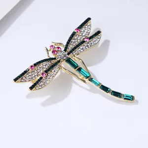 Close-up detail shot of the elegant rhinestone dragonfly brooch, glittering crystal and metal texture.