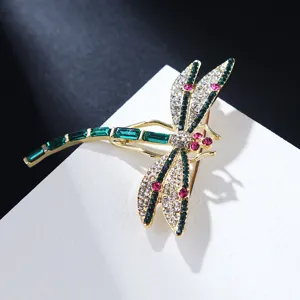 Elegant crystal dragonfly brooch with green and clear rhinestones on gold alloy.