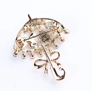 Spilla ad ombrello color oro con strass colorati e fiocco accessorio elegante per donne.