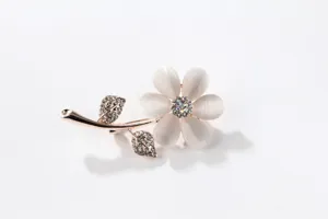 Elegant cat eye stone flower brooch detail closeup, sparkling crystal leaf accessories.