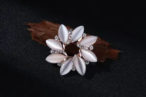 Detailaufnahme einer glänzenden Katzenauge-Stein und Strass Blumenbrosche in Roségold.