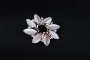 Nahaufnahme einer eleganten Blumenbrosche mit weißen Katzenauge-Blütenblättern und Strass.