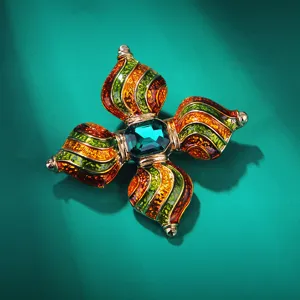 Nahaufnahme einer retro Barock Kreuz Brosche mit bunter Emaillierung und grünem Stein.