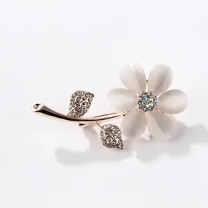 Elegant rose flower brooch pin with white cat's eye petals and rhinestone in rose gold.