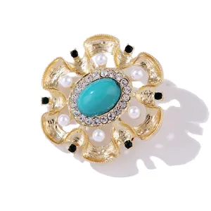 Detalle del broche vintage barroco dorado con piedra turquesa y brillantes pedrerías finas.
