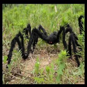 Close-up view of a large black plush spider decoration placed in outdoor grass for Halloween.