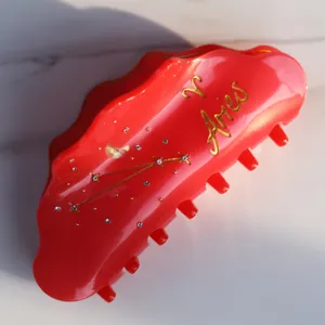 Rote Acetat Haarklammer mit goldenem Widder Sternbild Design für elegante tägliche Frisuren.
