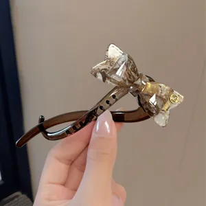 Vista detallada de la elegante pinza para el cabello con lazo de acetato marrón y estilo chic.