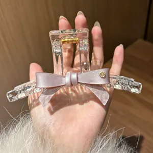 Detailansicht der klaren Acryl Haarklammer mit rosa Schleife und edlem Metallakzent.