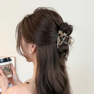 Détail de pince à cheveux triangle écaille, accessoire élégant pour coiffure demi-queue.