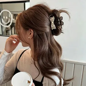 Detail view of a small hair claw clip with a chic polka dot bow, perfect for half-up hairstyles.