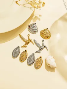 Detailed view of metal DIY jewelry pendants including hummingbirds, shells and oval portraits.
