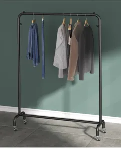 Detailansicht des schwarzen Metall-Kleiderständers mit Rollen und hängender Kleidung im Zimmer.