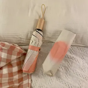 Vue détaillée d'un parapluie compact avec dégradé rose dans un cadre de chambre chaleureux.