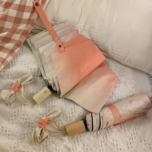Vue détaillée du parapluie pliant compact rose poudré anti-UV pour soleil et pluie.