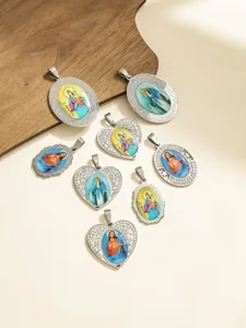 Dettaglio pendente ritratto religioso in acciaio inossidabile, forme ovali e cuori.