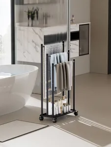 Detail view of the black metal freestanding towel rack with wheels and storage tray.