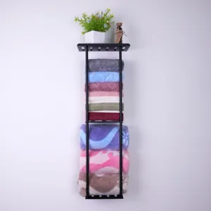 Black metal wall-mounted bathroom storage shelf featuring organized towels and plant decor.