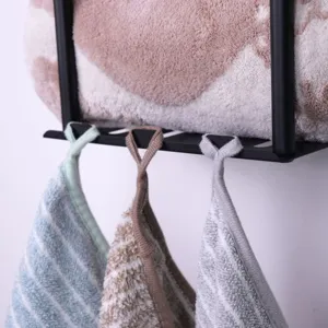 Detailed view of wall-mounted metal storage rack with hanging hand towels for bathroom use.