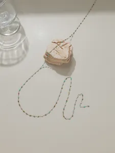 Gros plan de la chaîne délicate en acier inoxydable avec mini perles colorées vives.