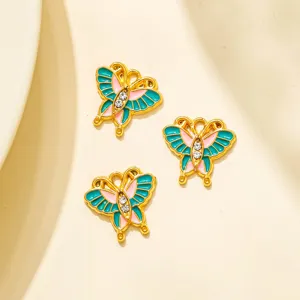 Gros plan de charmants pendentifs papillon en émail avec strass pour la création de bijoux.